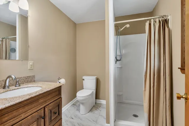 a bathroom with a granite countertop sink toilet and shower