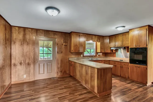 a kitchen with stainless steel appliances granite countertop a stove a sink dishwasher a refrigerator and a oven with wooden floor