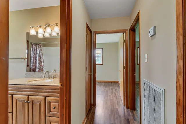 a view of a hallway with wooden floor and a dining room