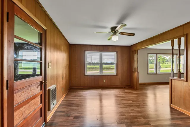 a view of an empty room with a window and wooden floor