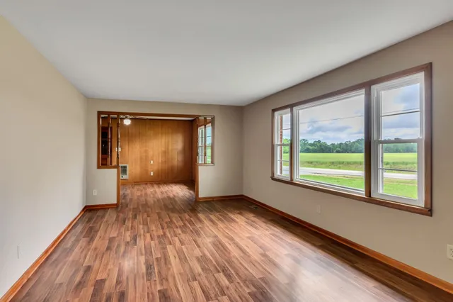 a view of an empty room with wooden floor and a window
