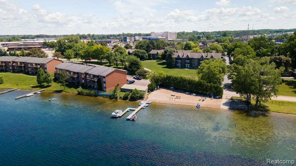 1974 Klingensmith Road, Unit 4 Bloomfield Hills, MI 48302 - Photo 30 of 35 Lakeside property featuring multiple brick apartment buildings, a private sandy beach, and two separate docks with boat slips