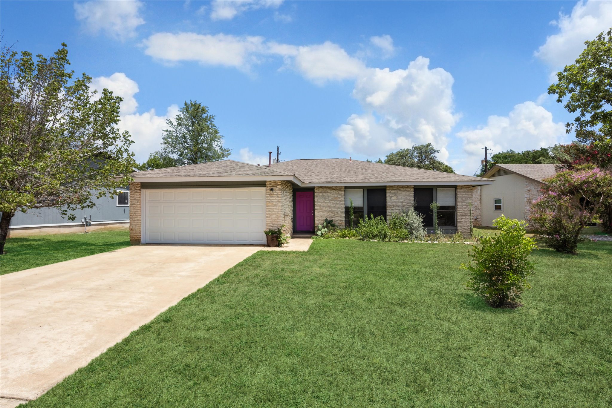 Single story home featuring an attached garage, driveway, a front lawn, brick siding, and roof with shingles