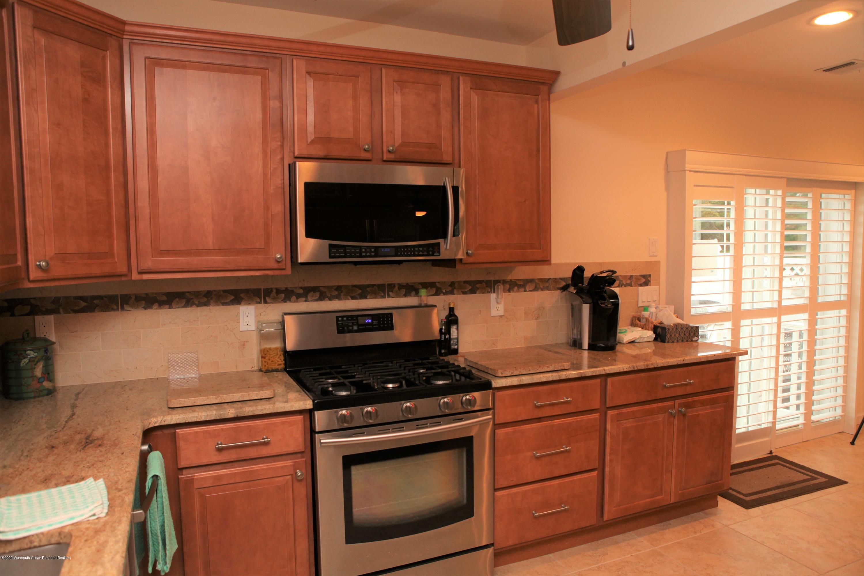 17 Colony Road Seaside Heights, NJ 08751 - Photo 21 of 37 a kitchen with granite countertop a stove top oven microwave and cabinets