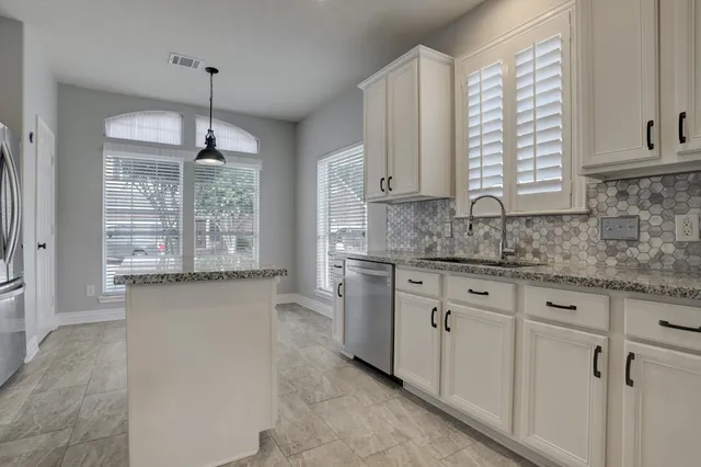 a kitchen with granite countertop white cabinets white appliances a sink and a window