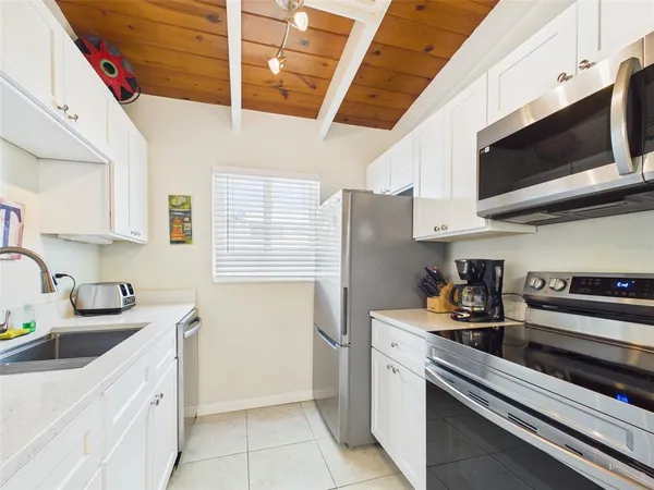 a kitchen with stainless steel appliances a sink dishwasher stove and microwave with wooden floor