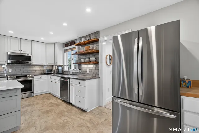 a kitchen with granite countertop stainless steel appliances a refrigerator stove top oven and sink