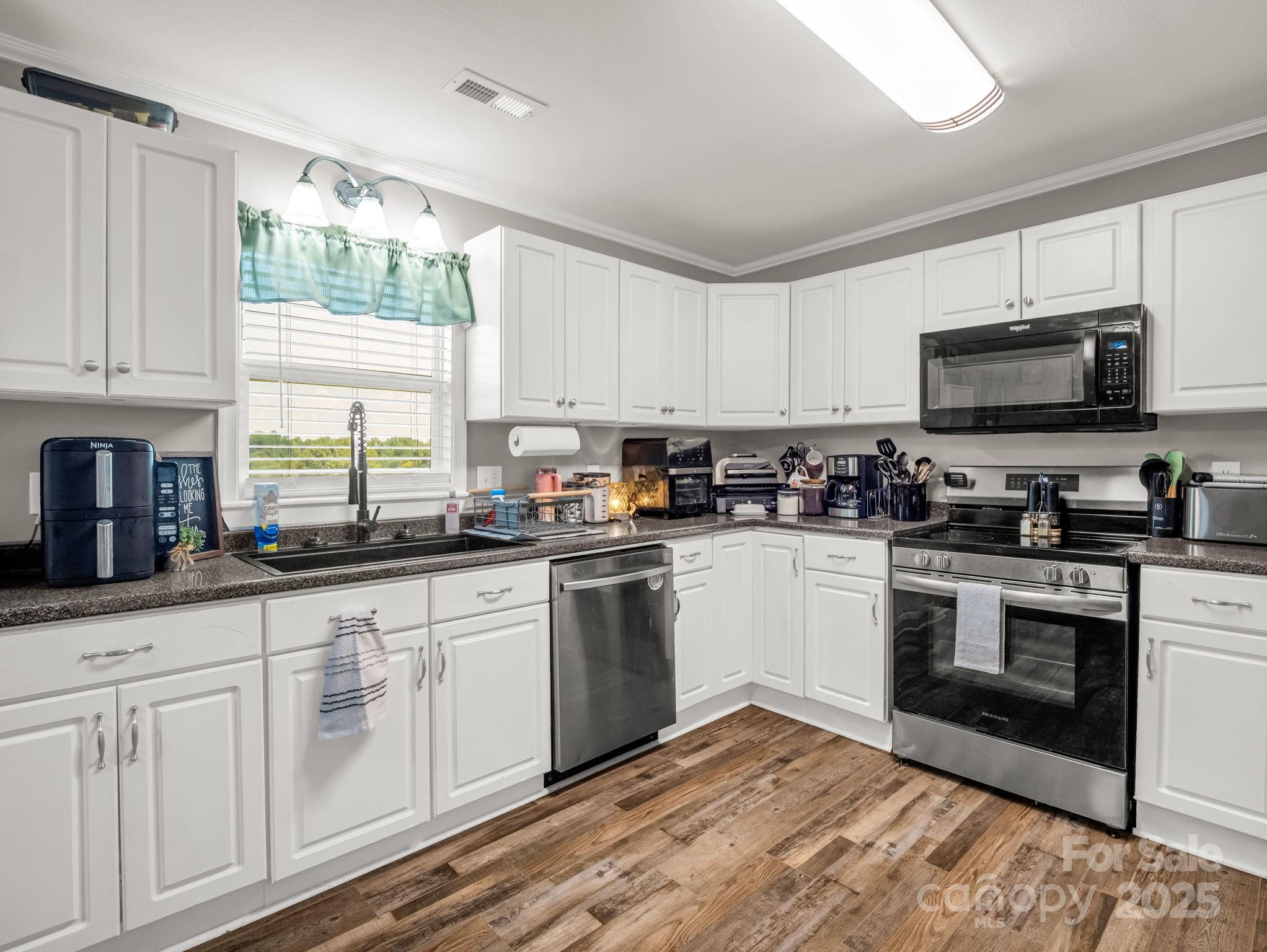 261 Faye Toney Road Mooresboro, NC 28114 - Photo 12 of 48 a kitchen with granite countertop white cabinets a sink a window and stainless steel appliances