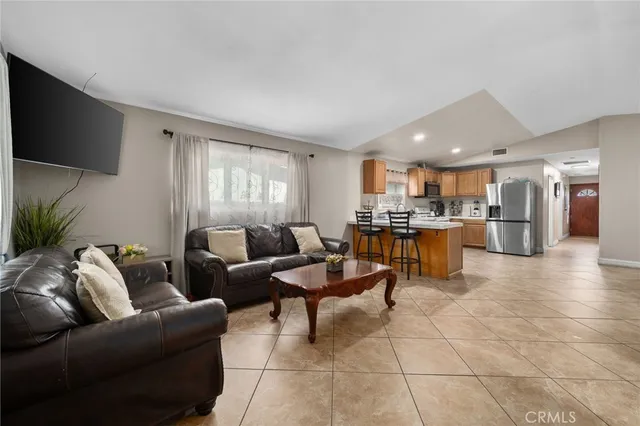 a living room with couches and kitchen view with wooden floor