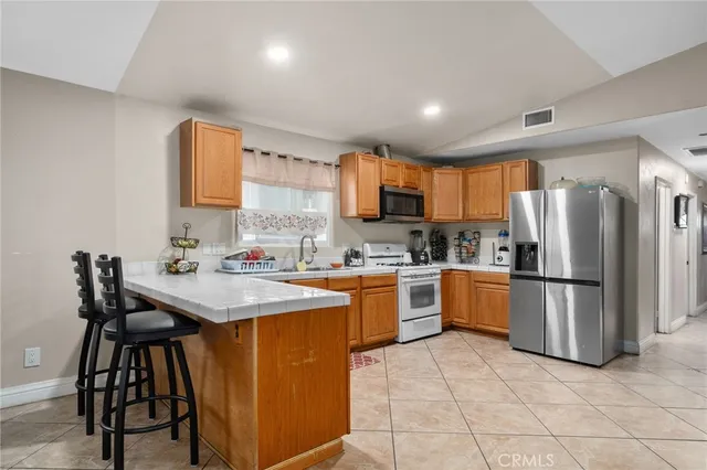 a kitchen with stainless steel appliances granite countertop a refrigerator a sink a stove a dining table and chairs