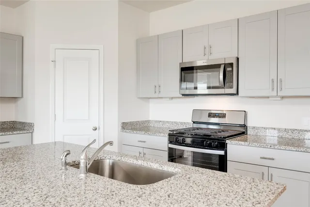 a kitchen with granite countertop a sink stove and cabinets
