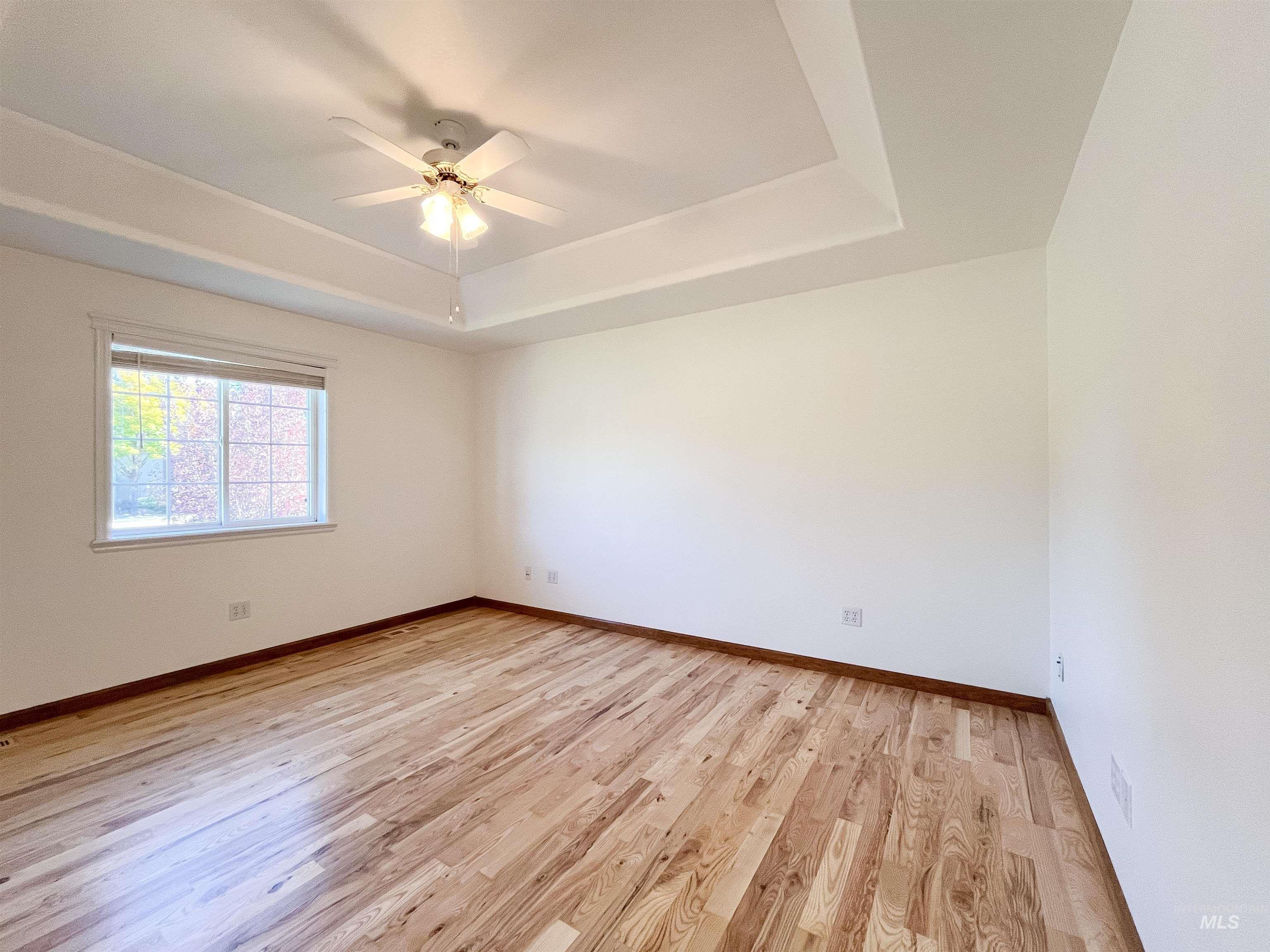 5231 North Morninggale Way Boise, ID 83713 - Photo 12 of 44 Spare room featuring light wood-style flooring, a tray ceiling, and a ceiling fan