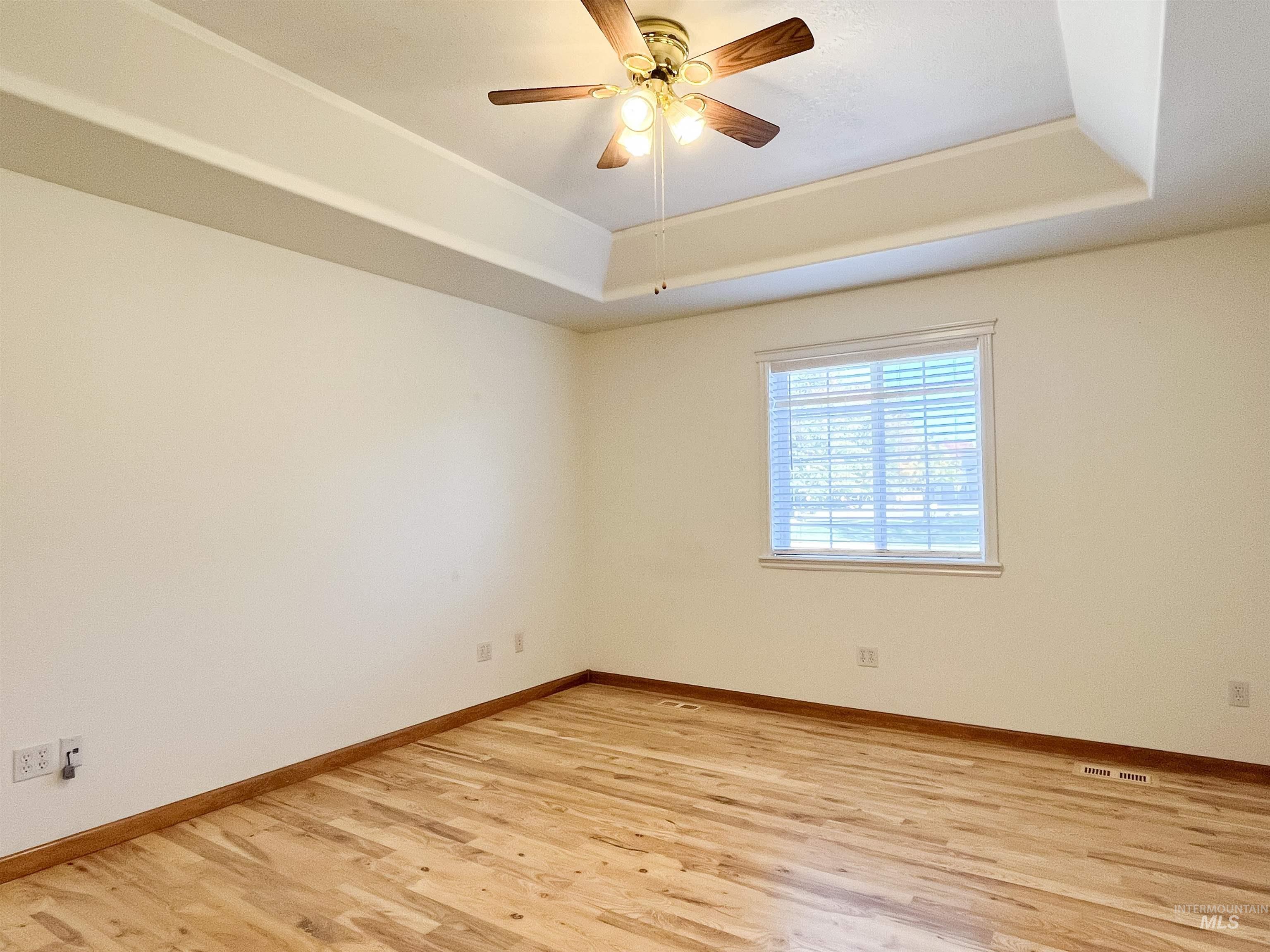 5231 North Morninggale Way Boise, ID 83713 - Photo 15 of 44 Unfurnished room with light wood-style flooring, a tray ceiling, and a ceiling fan