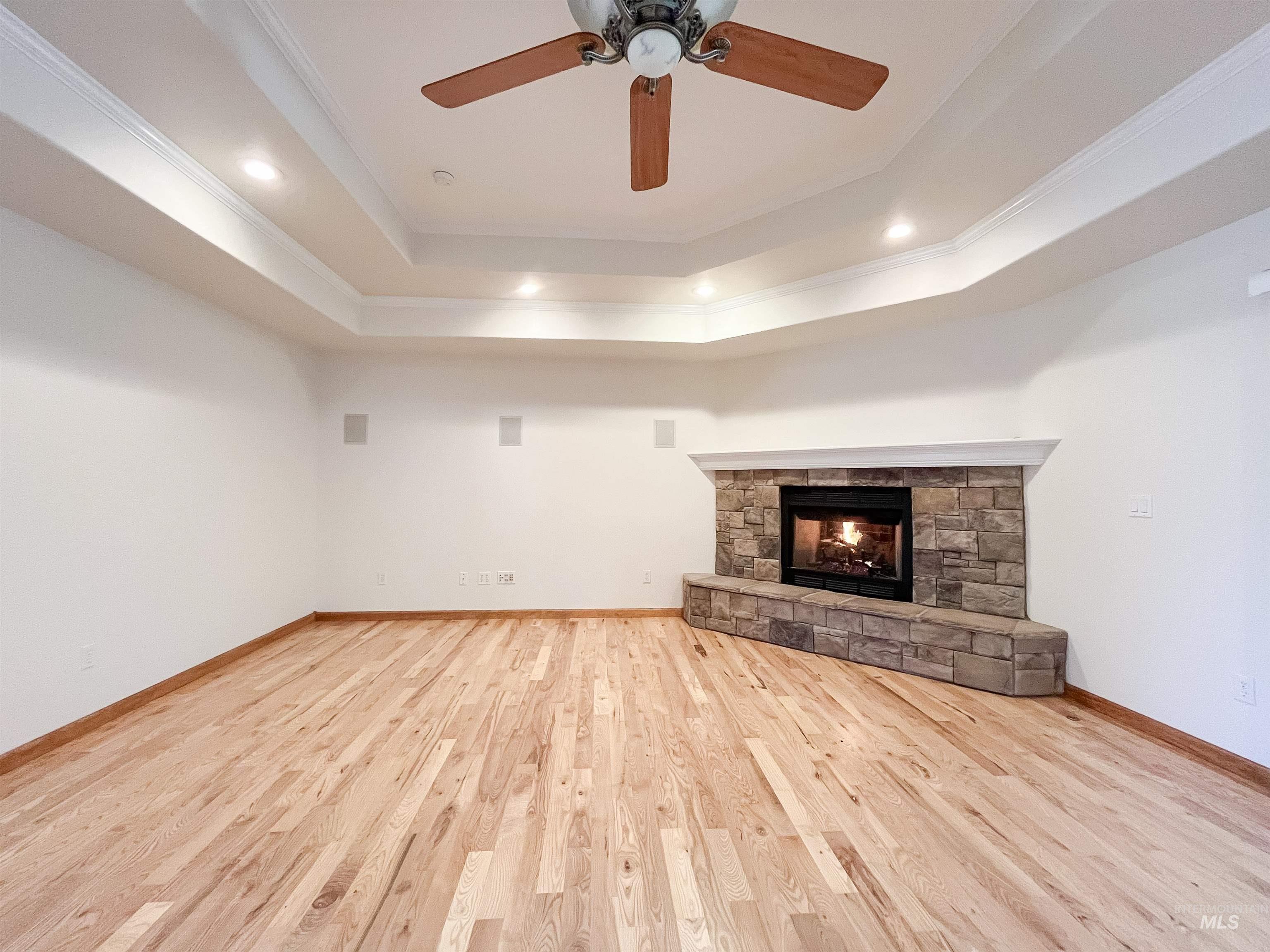 5231 North Morninggale Way Boise, ID 83713 - Photo 4 of 44 Unfurnished living room with a stone fireplace, light wood-style flooring, a ceiling fan, recessed lighting, and ornamental molding