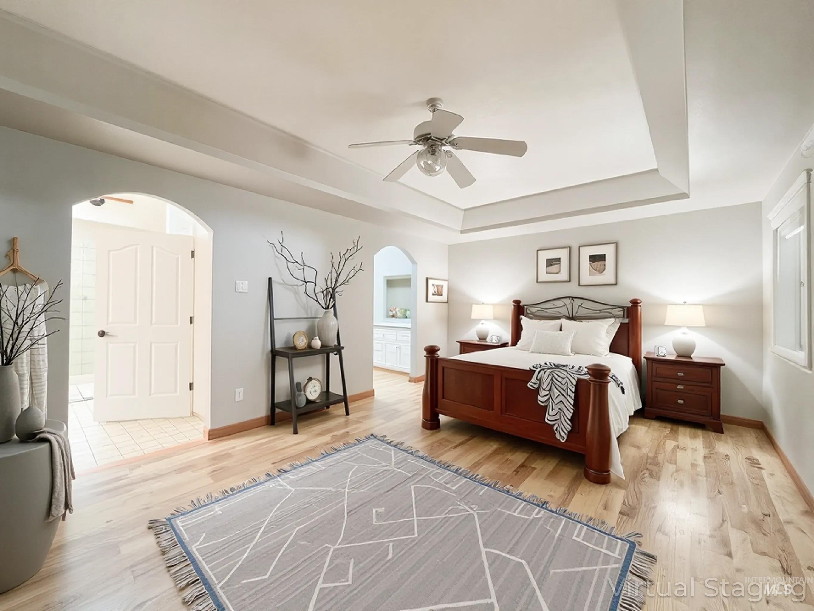 5231 North Morninggale Way Boise, ID 83713 - Photo 7 of 44 Bedroom with arched walkways, light wood finished floors, a ceiling fan, a tray ceiling, and connected bathroom and walk in closet.