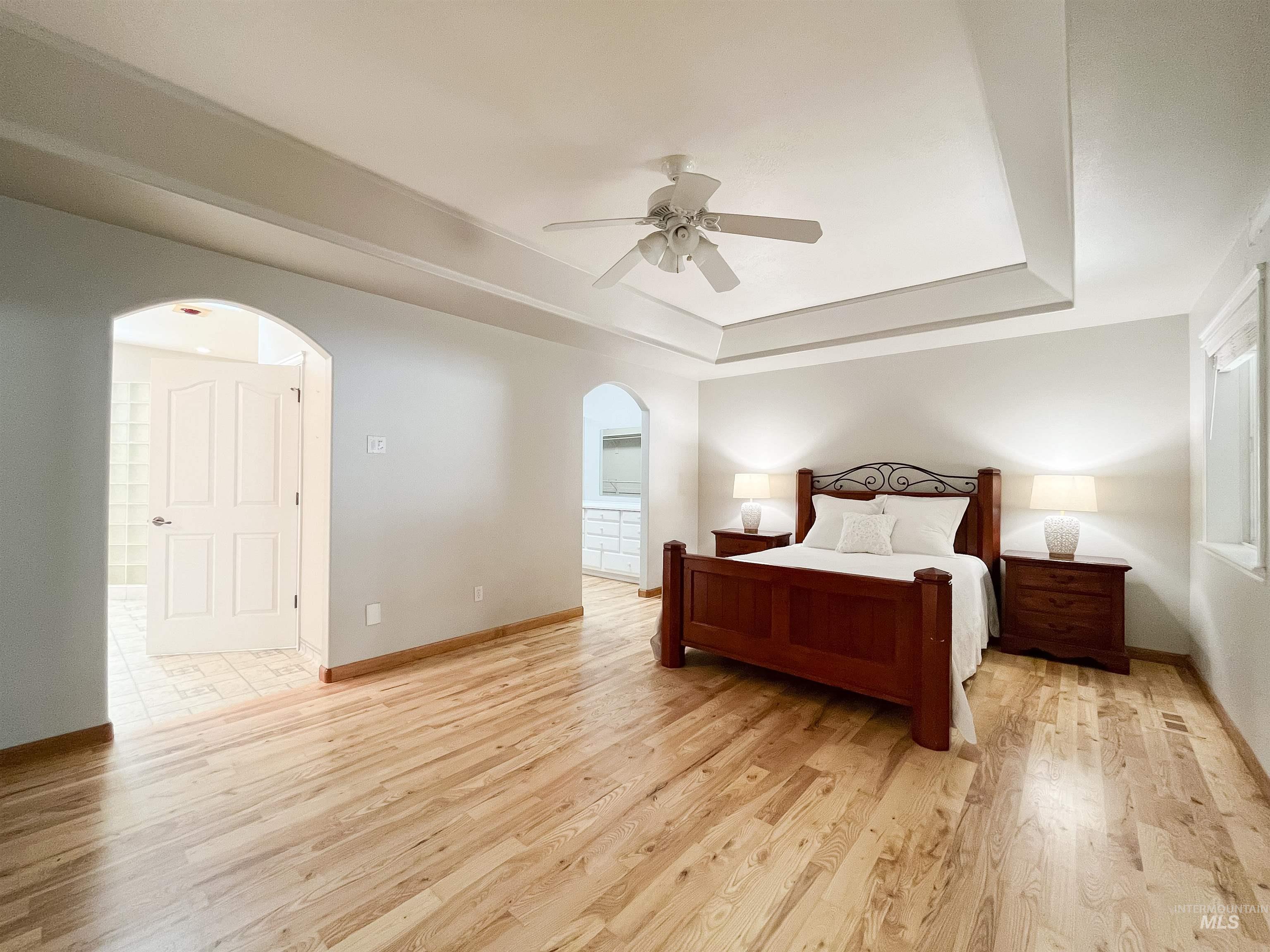 5231 North Morninggale Way Boise, ID 83713 - Photo 8 of 44 Bedroom with arched walkways, light wood-type flooring, a ceiling fan, and a raised ceiling
