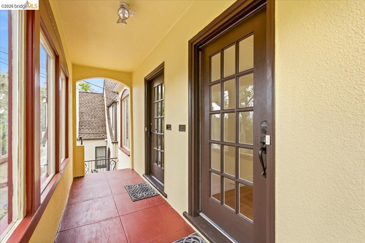 2403 Cedar Street Berkeley, CA 94708 - Photo 3 of 33 Covered entry porch featuring a paneled door with glass inserts, red tile flooring, textured exterior walls, and multiple casement windows with dark trim