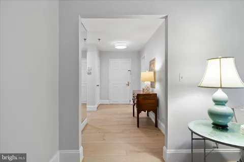 a view of a hallway with wooden floor and a bathroom