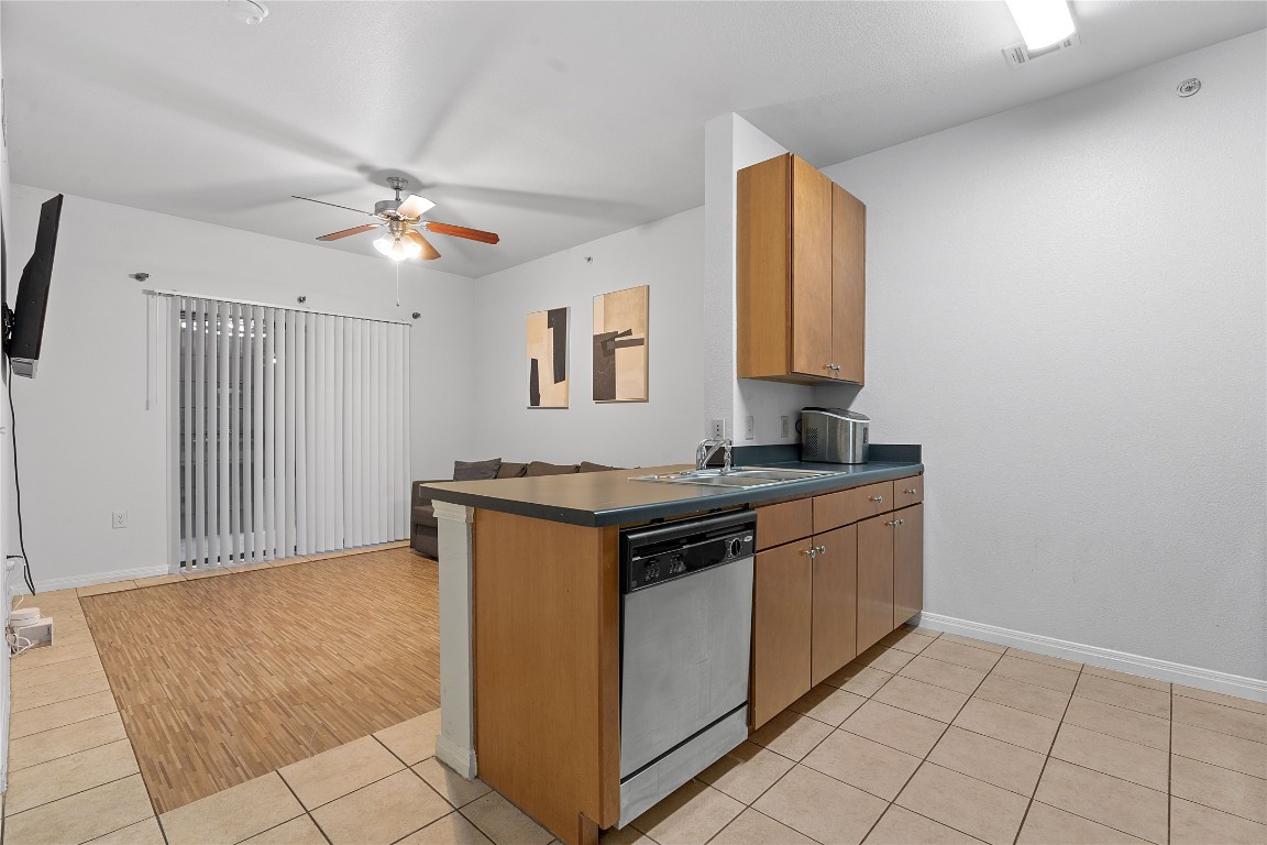 2515 Pearl Street, Unit 508 Austin, TX 78705 - Photo 15 of 25 Kitchen with stainless steel dishwasher, a peninsula, dark countertops, and light tile patterned floors