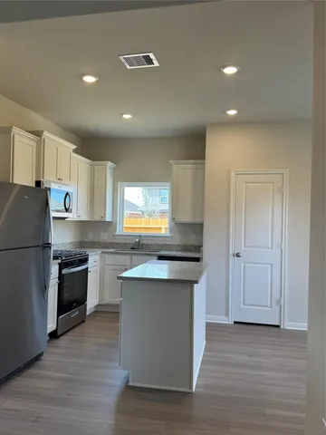 a kitchen with kitchen island granite countertop a sink cabinets and stainless steel appliances