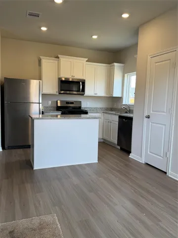 a kitchen with a sink a microwave a refrigerator and cabinets