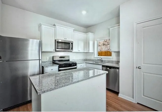a kitchen with granite countertop a refrigerator stove and microwave