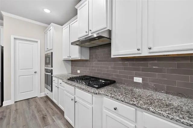 a kitchen with granite countertop white cabinets and a stove