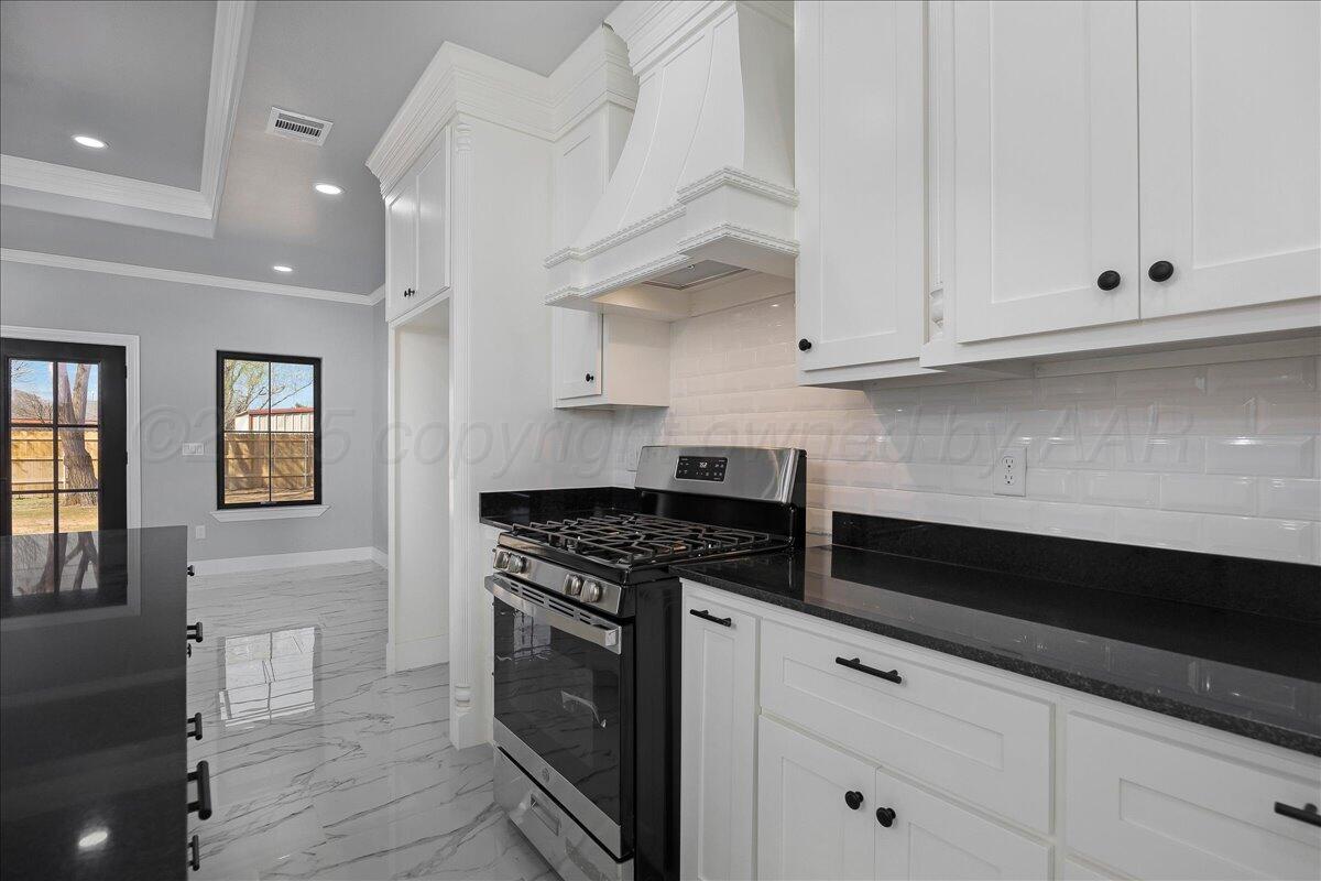 907 Oak Avenue Panhandle, TX 79068 - Photo 11 of 30 a kitchen with granite countertop white cabinets and black appliances