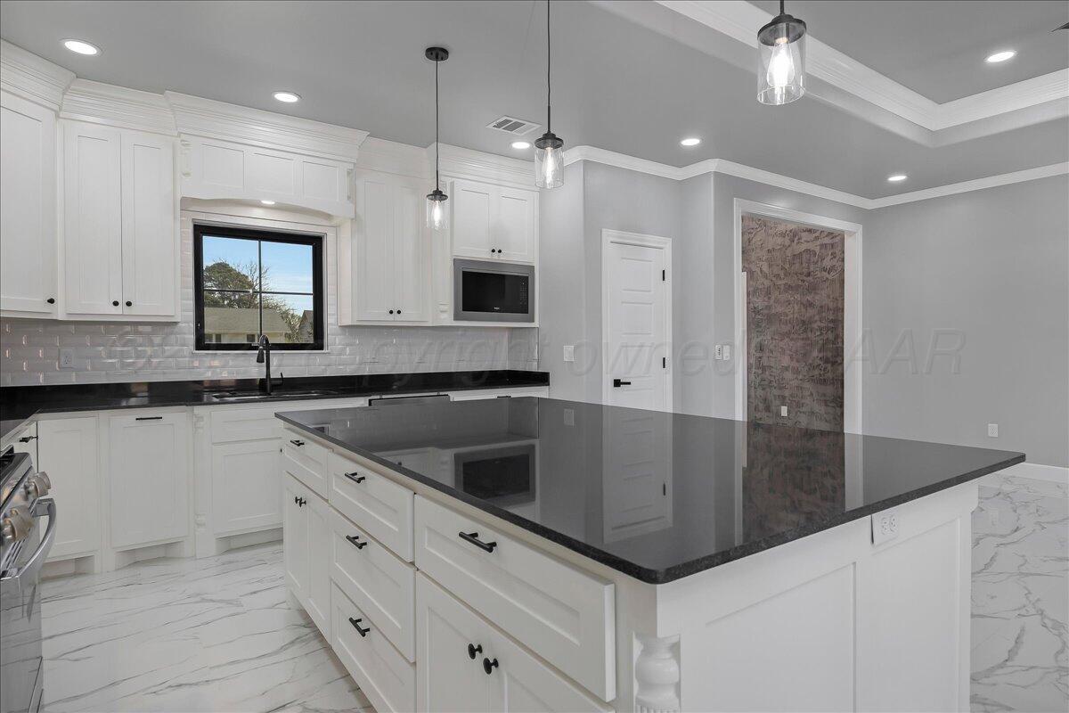 907 Oak Avenue Panhandle, TX 79068 - Photo 12 of 30 a kitchen with kitchen island granite countertop a sink window and cabinets