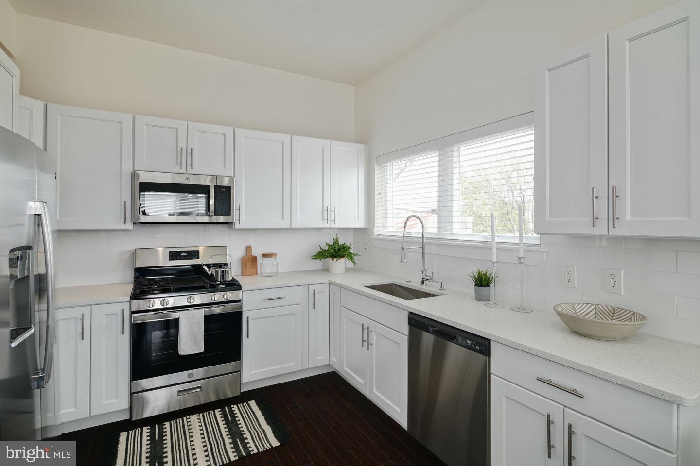 a kitchen with granite countertop white cabinets white stainless steel appliances a sink and a window