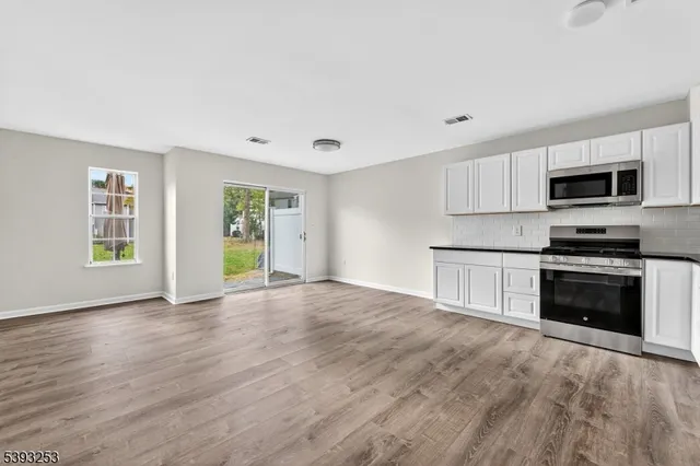 a kitchen with granite countertop a stove a microwave and a hard wood floors