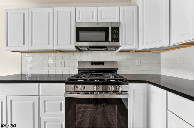 a kitchen with stainless steel appliances granite countertop white cabinets stove top oven and granite counter top