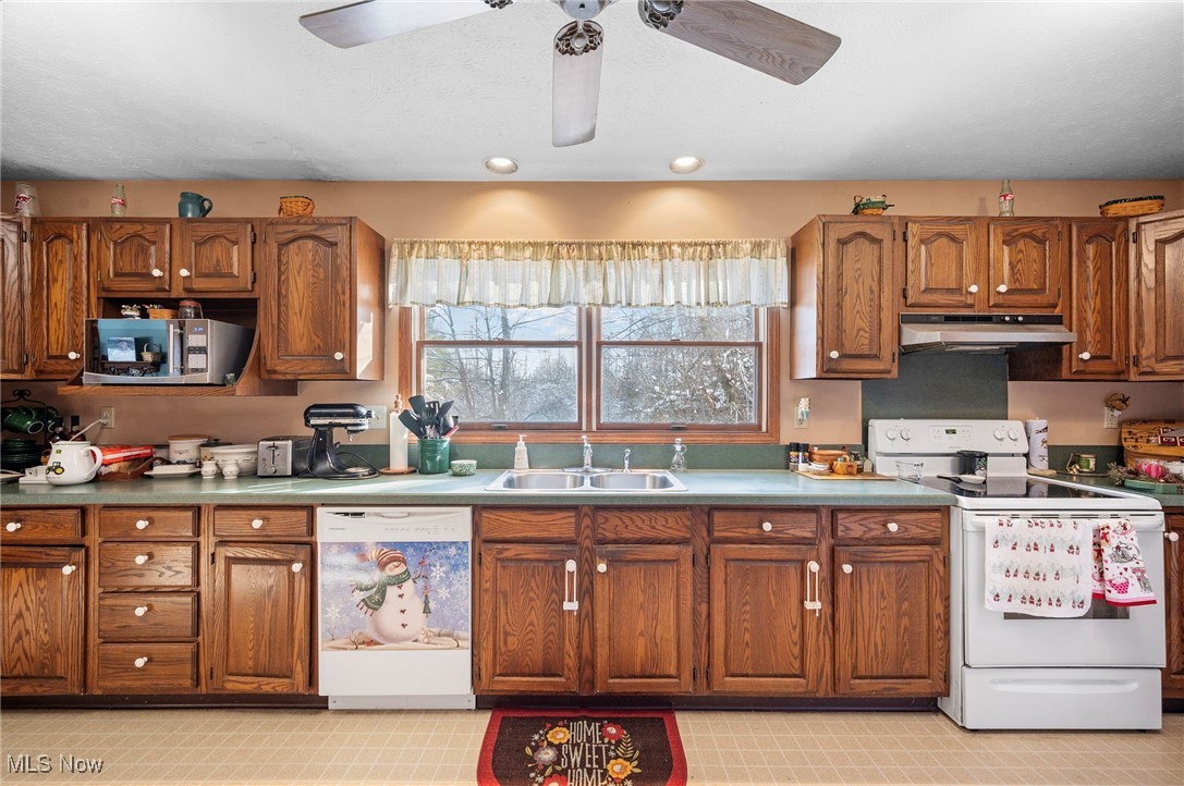 636 Wall Road Wadsworth, OH 44281 - Photo 11 of 35 Kitchen featuring under cabinet range hood, white appliances, a sink, light countertops, and brown cabinetry