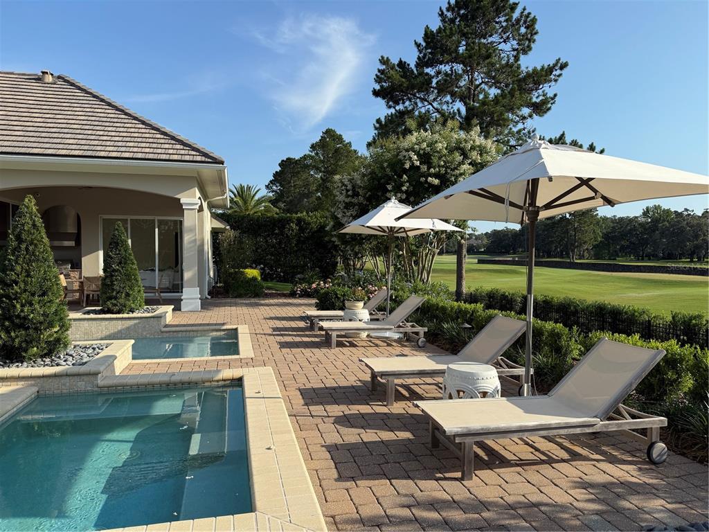 8761 Northwest 31st Lane Road Ocala, FL 34482 - Photo 19 of 25 a view of a patio with couches and table and chairs under an umbrella with a fire pit