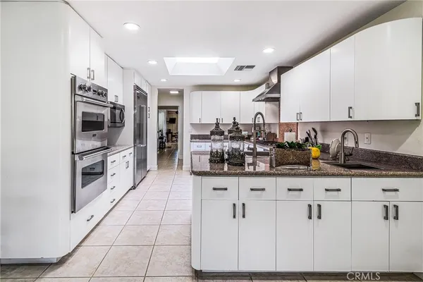 a large kitchen with stainless steel appliances lots of counter space sink and a mirror