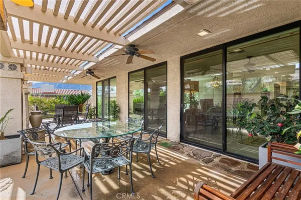 a view of a patio with table and chairs potted plants with floor to ceiling window