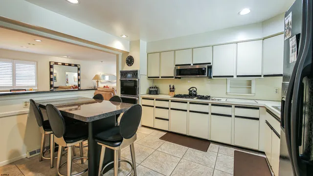 a kitchen with stainless steel appliances granite countertop a sink a stove a refrigerator cabinets and chairs