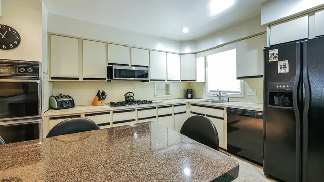 a kitchen with granite countertop a refrigerator stove and sink