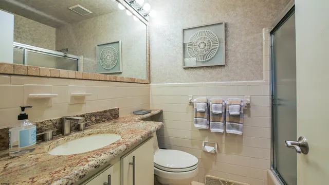 a bathroom with a granite countertop toilet a sink and a mirror