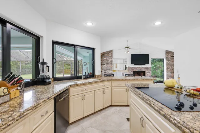 a kitchen with granite countertop a refrigerator a sink and white cabinets
