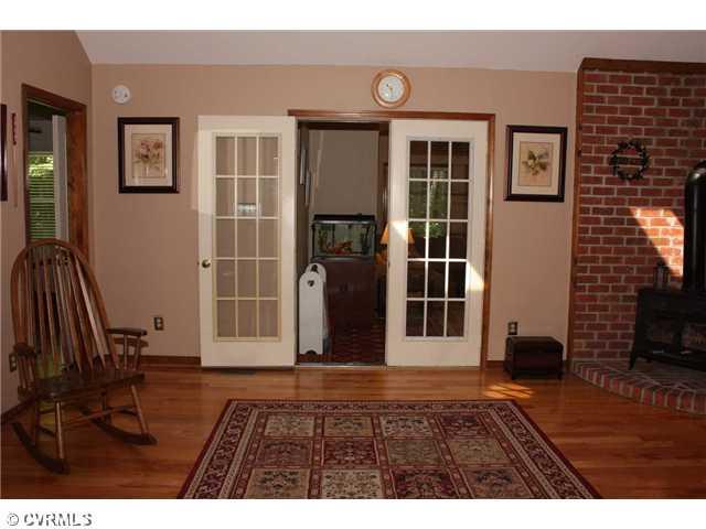 12103 Chatham Road Prince George, VA 23875 - Photo 13 of 18 Living Room - Hardwood floors, brick surrounding the wood stove and vaulted ceilings. Double doors to family room / Florida room.