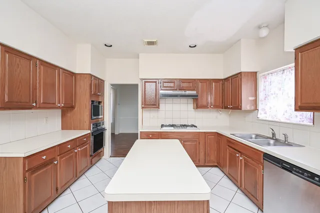 a large kitchen with stainless steel appliances wooden cabinets a sink and a stove