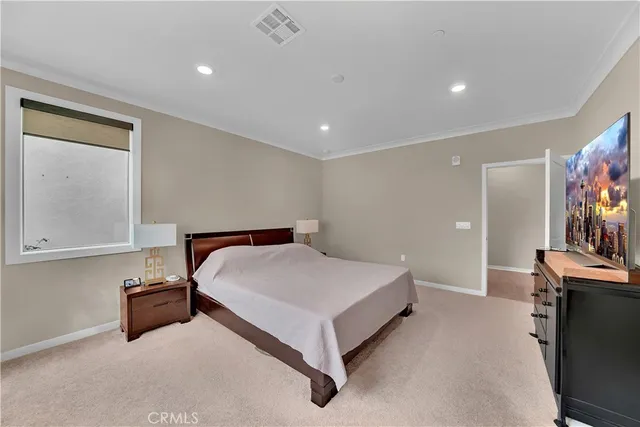 a spacious bedroom with a bed and a flat screen tv