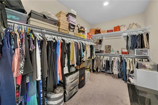 a view of walk in closet with clothes and shoes