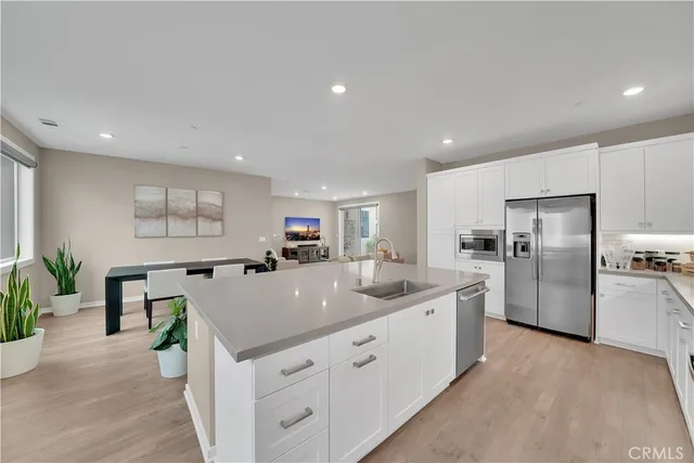 a large kitchen with stainless steel appliances kitchen island a large counter top and a refrigerator
