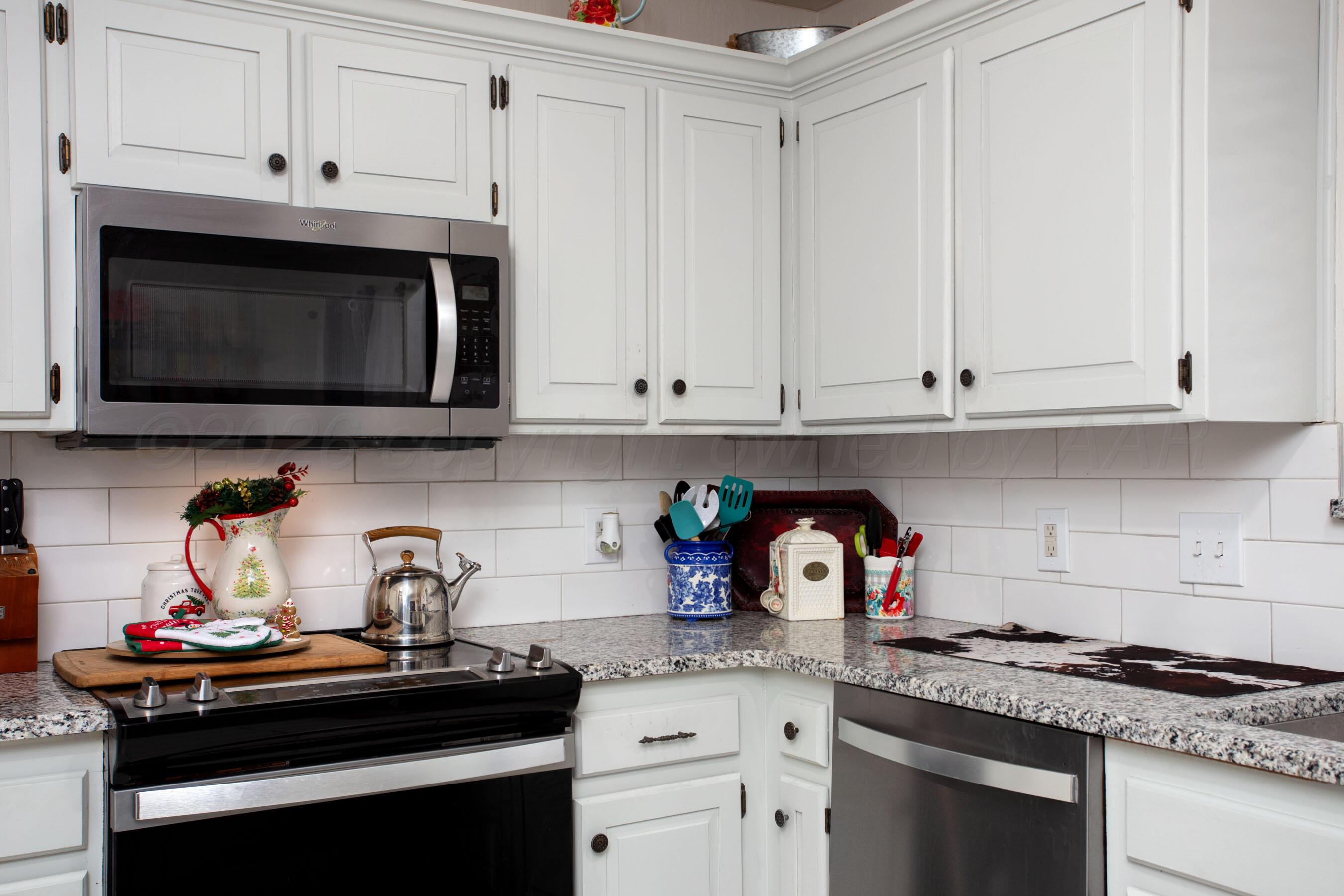 2907 Mable Drive Canyon, TX 79015 - Photo 4 of 23 a kitchen with stainless steel appliances granite countertop white cabinets a stove and a microwave