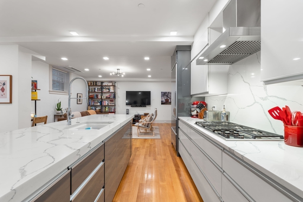 1762 Beacon Street, Unit 1 Brookline, MA 02445 - Photo 3 of 17 a large kitchen with stainless steel appliances kitchen island granite countertop a large stove a sink dishwasher and cabinets with wooden floor
