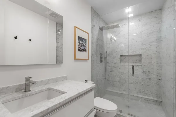 a bathroom with a granite countertop sink a toilet and shower