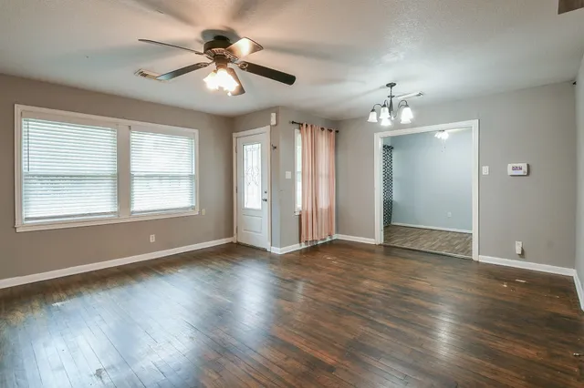 a view of an empty room with wooden floor and a window