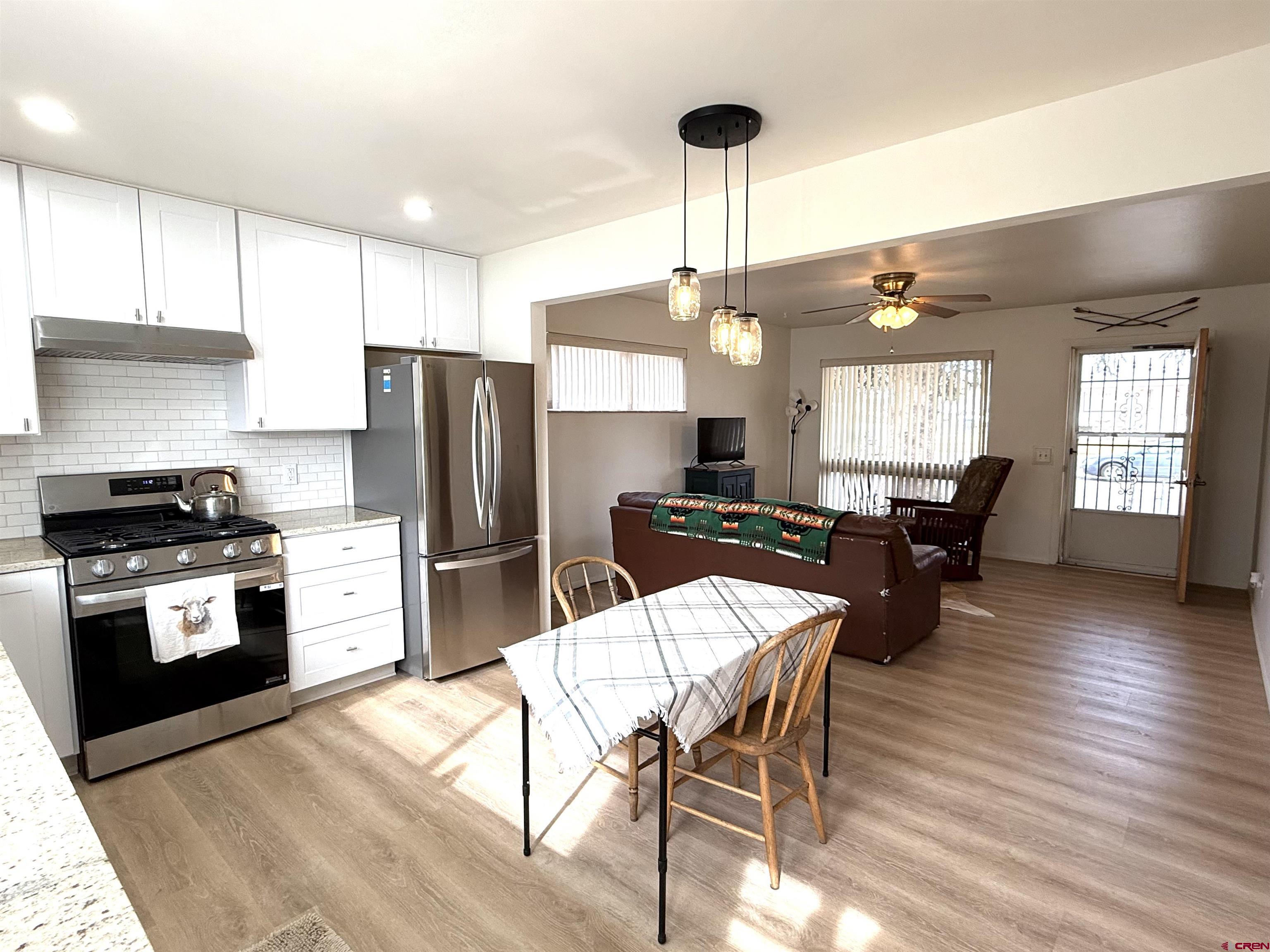 801 East 3rd Street Cortez, CO 81321 - Photo 14 of 22 a kitchen with stainless steel appliances kitchen island granite countertop a refrigerator a stove and white cabinets with wooden floors